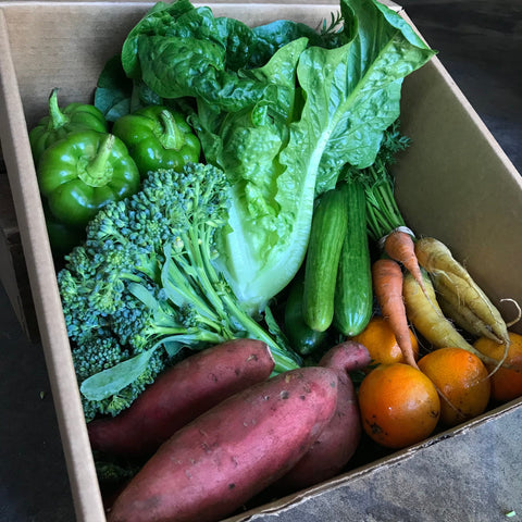 CSA produce box brimming with fresh organic vegetables, including green leafy greens, potatoes, and carrots. Highlights the variety of seasonal farm-to-table produce in each delivery, perfect for those seeking local organic food options.