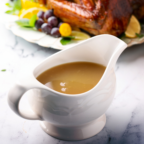  A rich and savory beef bone broth gravy in a gravy boat, with a smooth, thickened texture, ready to be served over meats and potatoes.