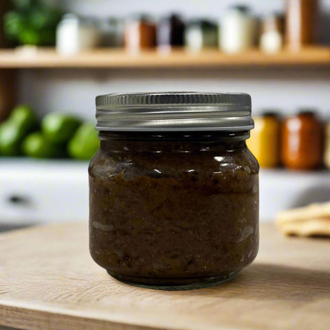 Close-up of a jar of Aged Black Bean Miso, showing the rich, dark texture of the miso inside. The label reads 'Buddha's Garden LLC' with the weight of 10 oz displayed prominently. The jar is set against a neutral background, highlighting the deep, umami-rich color of the miso.