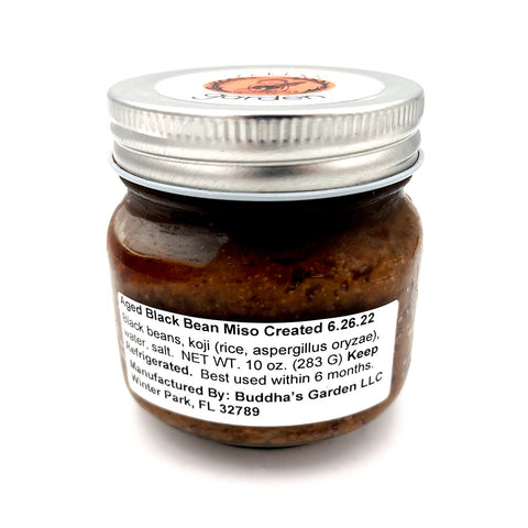 A jar of Buddha's Garden Aged Black Bean Miso, showcasing a rich, dark blend of fermented black beans and umami-packed miso. This savory and earthy miso brings a bold, aged complexity to soups, marinades, and sauces, perfect for adding a deep umami kick to your dishes.